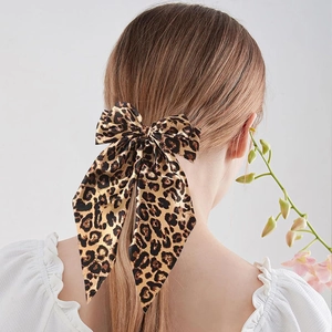 Detail of elegant large leopard print bow hair clip with silky satin texture on hair