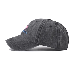 Detailed close-up of pink flamingo embroidery on vintage grey washed denim baseball cap