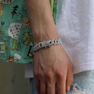 Close-up of iced out silver Cuban link bracelet with diamond-encrusted clasp on wrist