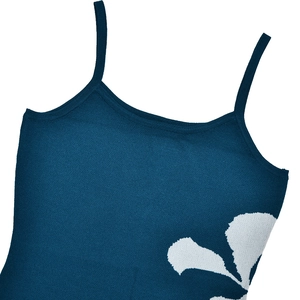 Détail d'un camisole en tricot bleu avec motif floral blanc et fines bretelles