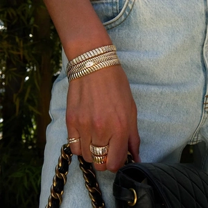 Detailed view of layered 10mm golden tennis chain bracelet and rings on hand