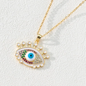 Macro shot of evil eye pendant with white enamel, colorful zircons and gold chain