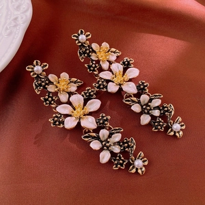 Macro detail of French floral drop earrings with white enamel petals and pearls