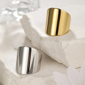 Detailed view of wide polished gold and silver rings on natural white stone surface