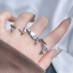 Detail of three-piece silver ring set featuring a blue eye motif and dangling charms