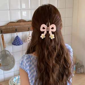 Pink and white striped bow hair claw with floral accents on a model's wavy hair