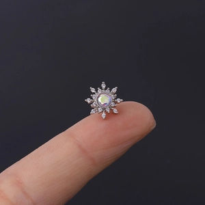 Detailed close-up showing a tiny silver snowflake stud earring with a colorful zircon