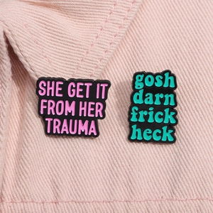 Macro view of quote enamel pins on pink denim with slogans and black alloy finish