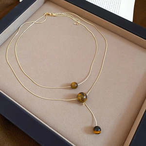 Detail of double-layered gold tiger eye stone necklace with adjustable clasp and chain