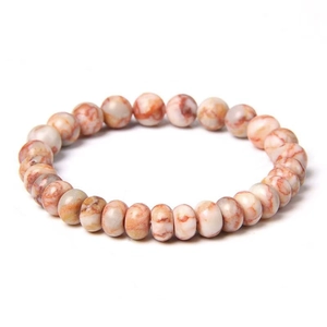 Détail de perles en pierre de 8mm crème avec veines oranges sur un bracelet minimaliste