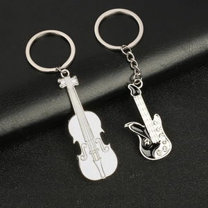 Guitar and violin metal keychains with crystal details on black leather texture