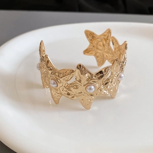 Detailed macro view of gold starfish bracelet with textured metal and white pearls