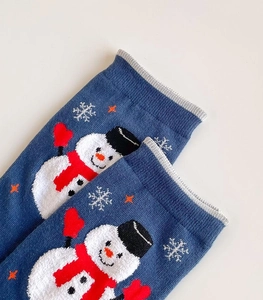 Close-up of blue terry cloth Christmas socks featuring woven snowman and snowflake patterns