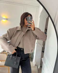 Détail de la veste en laine taupe zippée et du sac à main en cuir noir de luxe