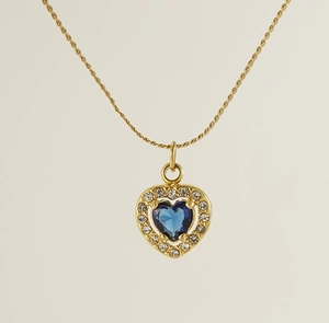 Detail view of gold heart necklace with blue center stone and sparkling zircons