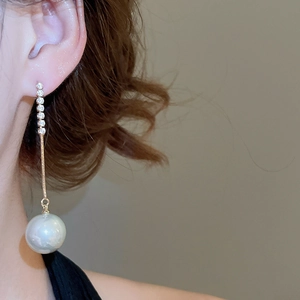 Detail of elegant gold tassel earrings with sparkling zircons and large white pearls