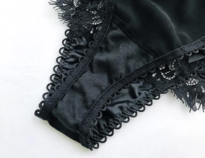 Dettaglio del pizzo nero elegante e del raso liscio su biancheria intima di lusso per donna
