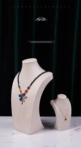 Detail of beaded dragonfly necklace and gold drop pendant on velvet bust displays
