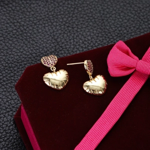 Elegant gold heart earrings with red zircon micro-paving on a red velvet jewelry box