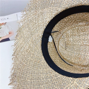 Vintage seagrass straw hat with frayed edges and breathable hollow weave for beach sun protection