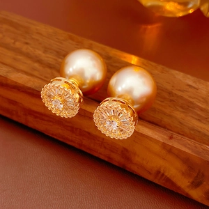 Detail of gold-plated pearl earrings with sparkling zircon floral accents on a wood stand