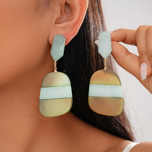 Close-up of geometric acetate oval earrings in translucent green and yellow tones