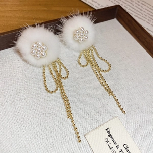 Detail view of elegant white pom-pom earrings with pearl clusters and golden tassels