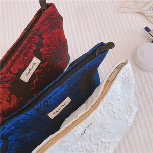 Detailed view of jacquard makeup bags with embossed sunflower texture and zip closure