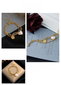 Close-up of double-layer gold chain bracelet with heart charm and engraved coin pendant
