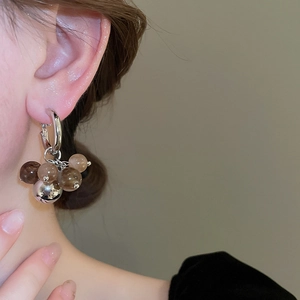 Detail of silver drop earring with gradient resin beads and metallic sphere on ear
