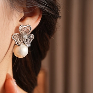 Close-up of vintage pearl earrings with silver woven flower design and zircon details