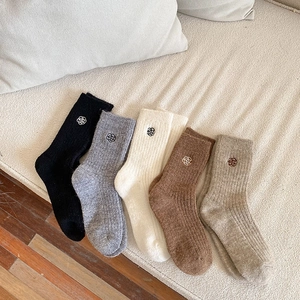 Detailed view of five pairs of winter thermal socks with small flower embroidery on a sofa