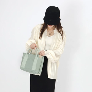 Detail of light green canvas tote bag showing durable texture and minimalist design