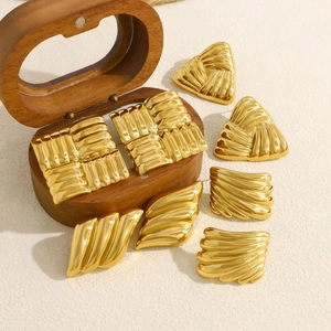 Close-up of golden geometric earrings with textured finish on a wooden jewelry box