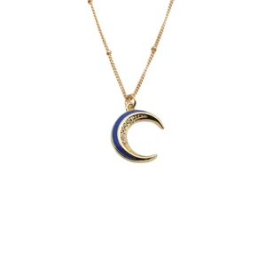Collana luna dorata con smalto blu e pendenti a stella in zircone su sfondo bianco