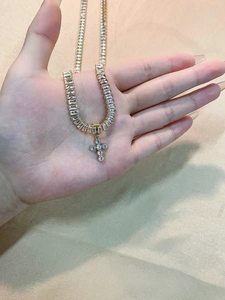 Close-up of golden cross pendant with zircon inlay on luxury champagne satin