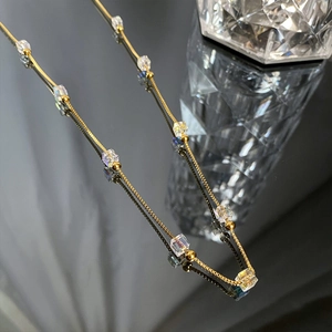 Macro shot of gold tone chain necklace with transparent cube beads on a mirror surface