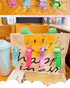 Close-up of colorful acrylic bear keychains with glitters hanging on a stylish canvas bag