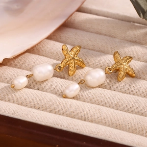 Detail of 18K gold starfish earrings with irregular pearls on a soft velvet jewelry box