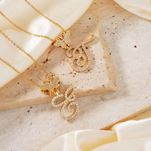 Macro shot of gold butterfly necklace with cursive letters and sparkling zircon stones