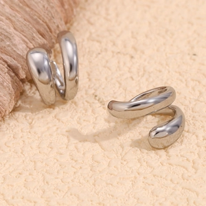 Dettaglio di ear cuff doppi in argento minimalisti con superficie curva lucida