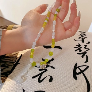 Detailed view of beaded bracelet with green jade beads and silver Fu character pendant