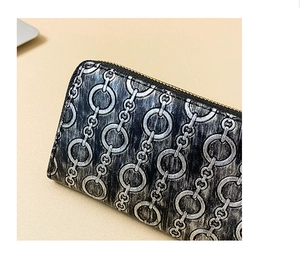 Detail of embossed chain pattern and golden zipper on women's long black wallet