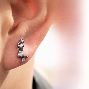 Close-up of vintage stainless steel mermaid stud earring on model with textured finish