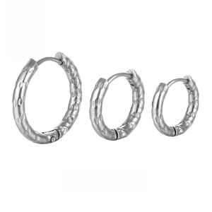 Macro detail of three hammered silver stainless steel hoop earrings in different sizes