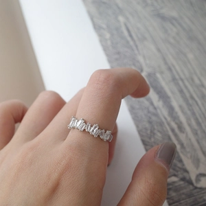 Close-up of sparkling rectangular zircons arranged irregularly on a silver open ring