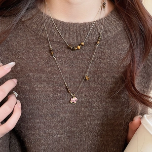 Détail d'un collier à deux rangs avec perles œil de tigre et pendentif cheval en émail rose
