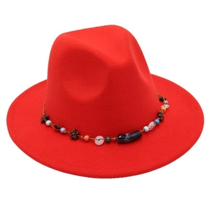 Detailed top view of red felt fedora hat with colorful beaded ethnic band and wooden flowers