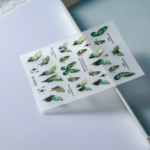 Macro detail of 5D embossed nail stickers featuring green butterfly designs with gold edges