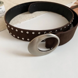 Ceinture en daim marron avec rivets argentés et boucle ovale sur un fond de bureau